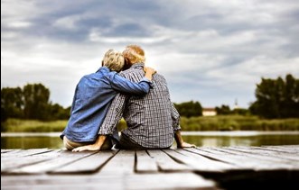 Two people sitting on a pier hugging